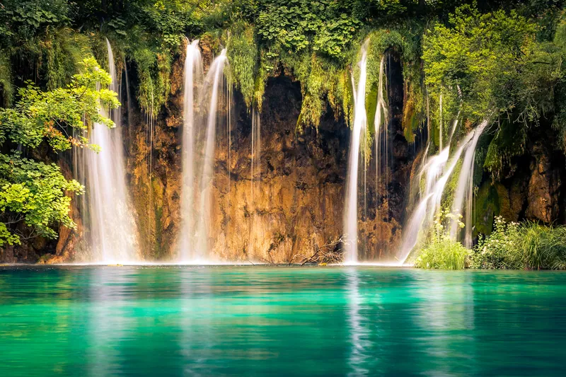 Waterfalls falling into a turquoise lake at Plitvice Lakes National Park