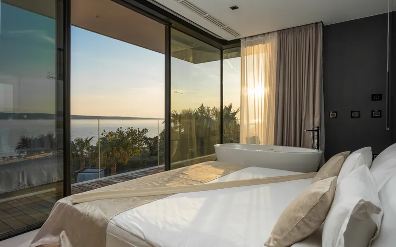 Bedroom at sunset behind floor-to-ceiling glass