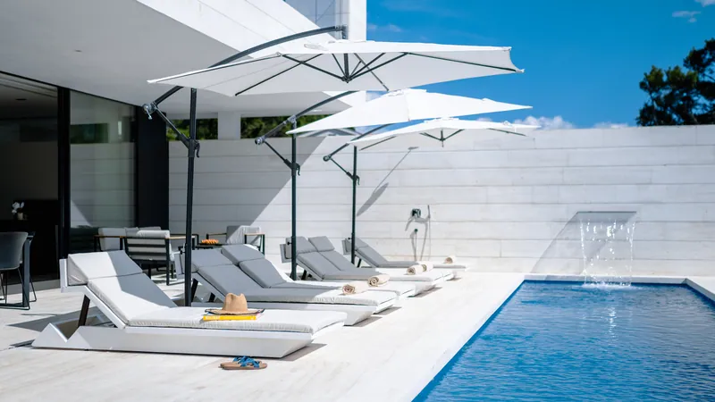 Sun loungers under parasols beside the pool and its waterfall