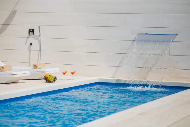 The pool waterfall with two cocktails on the stone edge