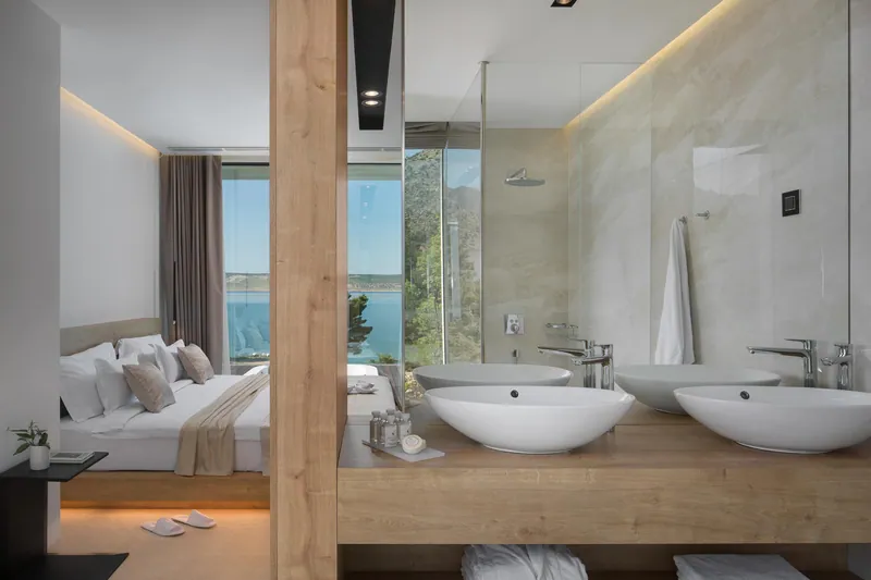 Bedroom and open bathroom with twin basins, the sea beyond