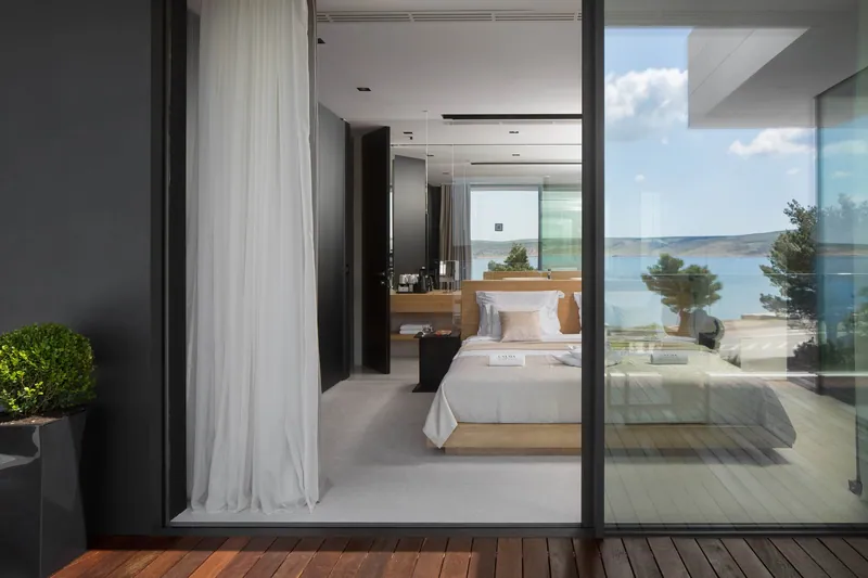 A bedroom seen from its terrace, with the sea reflected in the glass