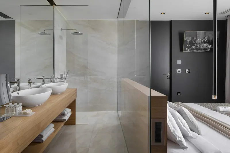 Open bathroom with twin basins and rain showers beside the bed
