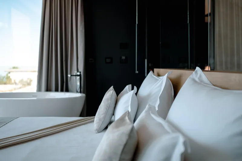 Pillows on the bed, with the freestanding bath by the window