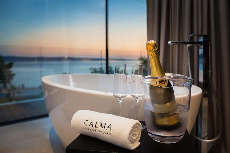 Sparkling wine beside the freestanding bath, the sea at dusk beyond