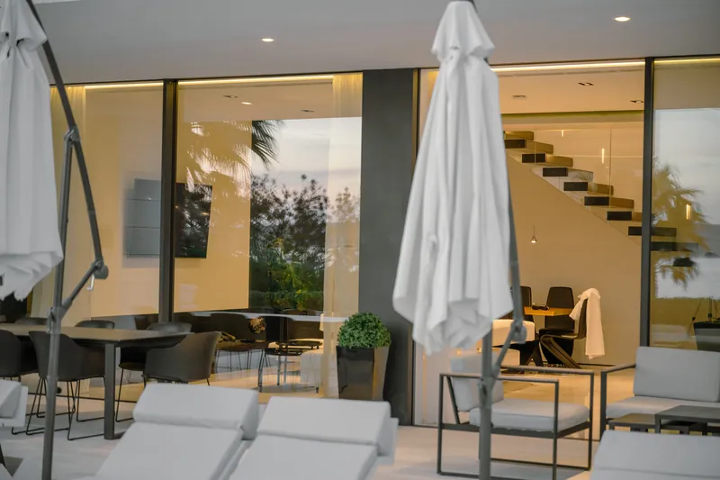 Covered dining terrace at dusk, with the floating staircase inside