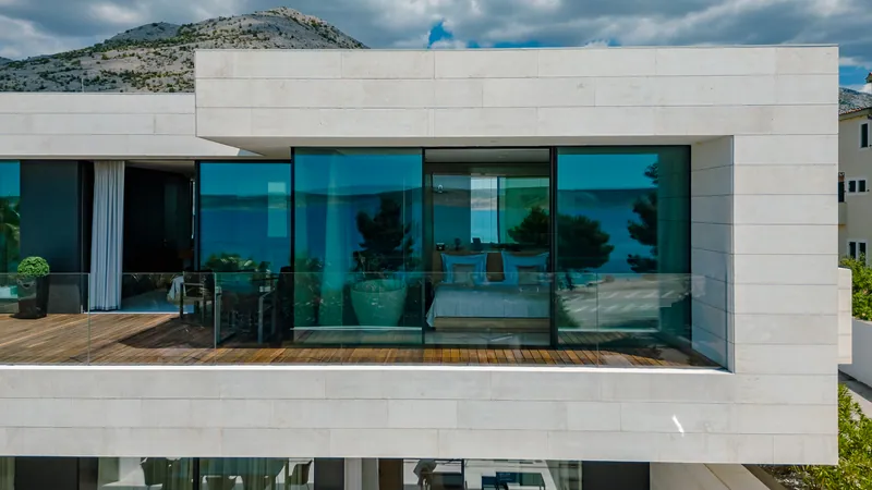 The upper terrace and a bedroom behind glass, with the sea reflected