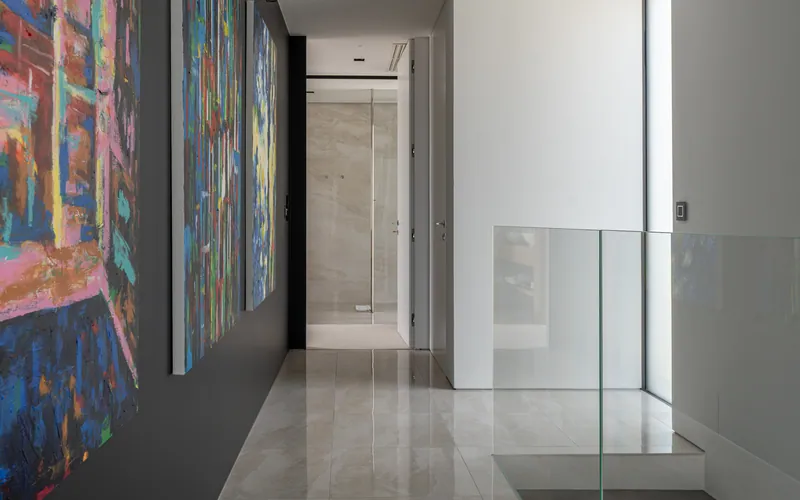 The upper landing, with paintings and a glass balustrade