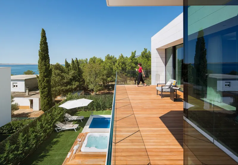 Upper timber deck overlooking the pool, the pines and the sea